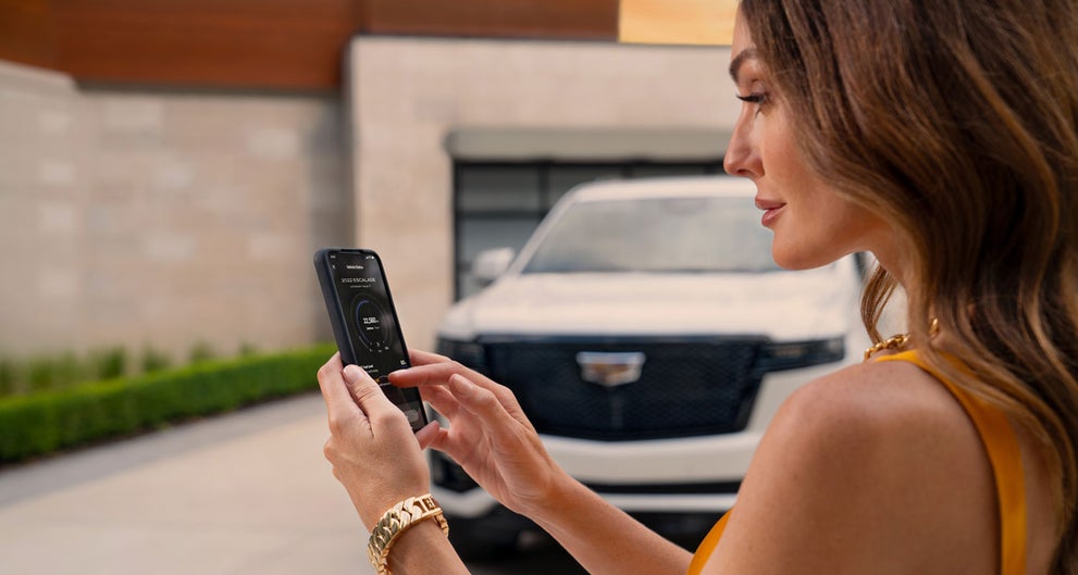 lady checking her mobile with a Cadillac vehicle background | Corwin Motors Kalispell Cadillac in Kalispell MT